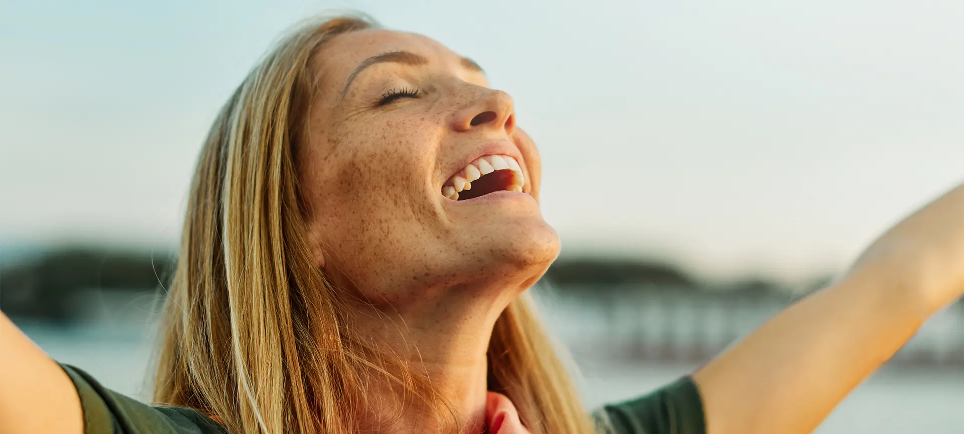 Femme souriante les bras levés, exprimant un soulagement ou une joie après un soutien émotionnel