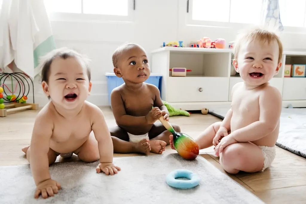 Trois bébés en couche jouant et souriant sur le sol d’une salle de jeux