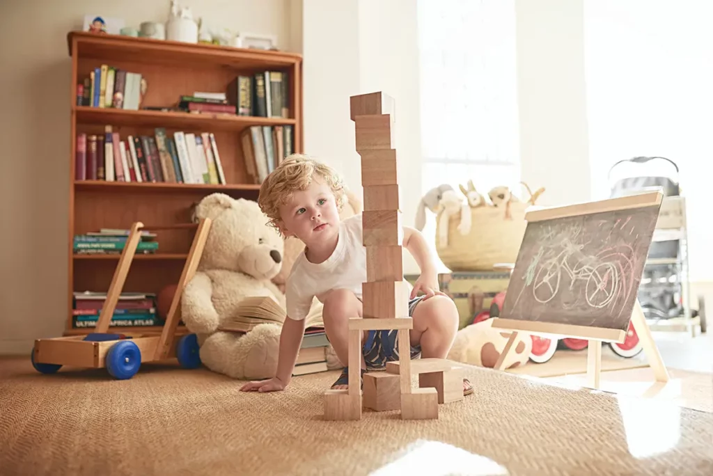 Jeune garçon jouant et construisant une tour en bois avec des cubes dans sa chambre