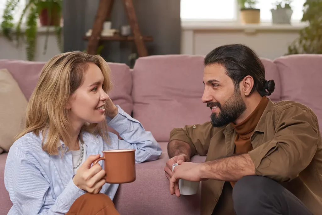 Jeune maman et jeune papa assis dans le salon en train de discuter autour d’un café