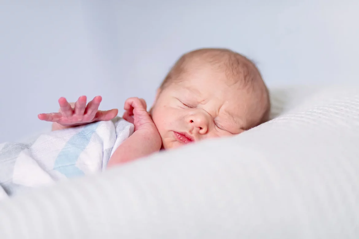 Nourrisson emmailloté en train de dormir paisiblement sur un lit blanc