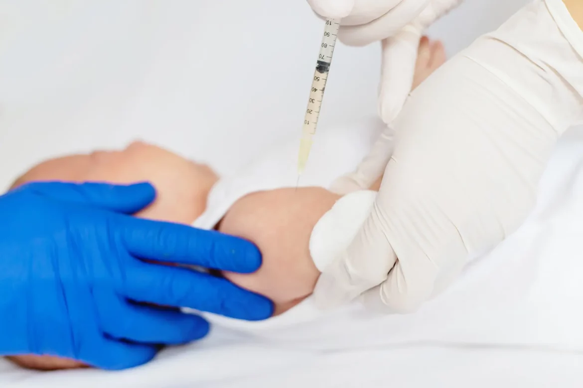 Un nourrisson reçoit une injection dans le bras, administrée par un professionnel de santé portant des gants médicaux