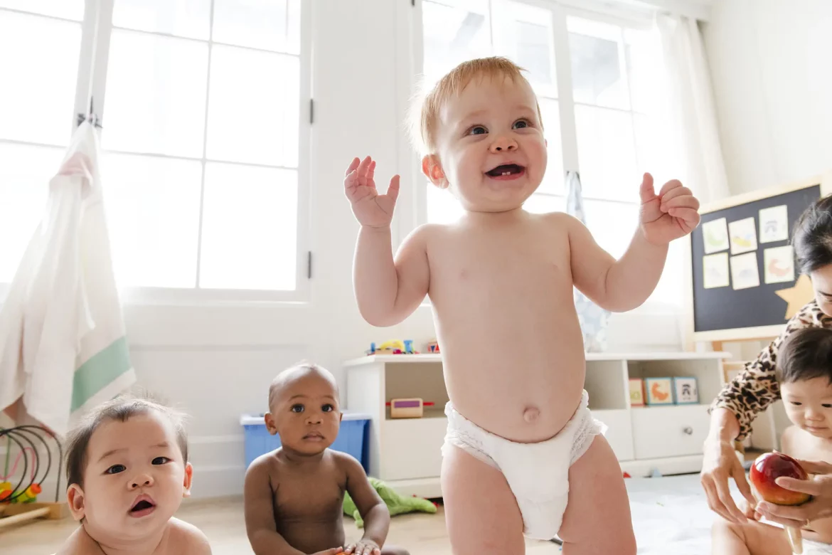 Plusieurs bébés en couche évoluant dans une salle lumineuse de crèche, souriants et en interaction, illustrant la garde d’enfant en 2025