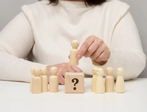 Future maman qui se questionne Femme représentant une future maman en train de choisir ou réfléchir à une décision, symbolisée par des figurines en bois et un cube avec point d'interrogation